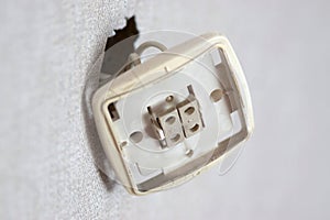 Exposed Electrical Socket With Missing Cover on a White Wall