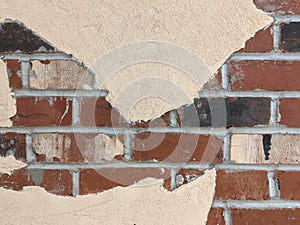 An exposed, red brick wall peeking out behind a tan paint job