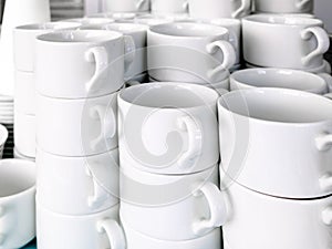 Exposed on stacks of white clean ceramic cups and saucers. Dishes in the restaurant for tea and coffee