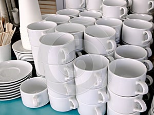 Exposed on stacks of white clean ceramic cups and saucers. Dishes in the restaurant for tea and coffee