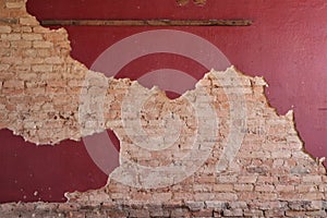 Exposed tan brick under red plaster wall with wood slat