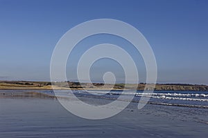 The exposed wet sand of the gently shelving beach at Lunan Bay as the Tide recedes. photo