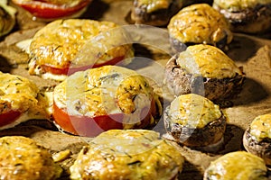 Exposition of baked mushrooms and tomato with cheese, tasty snacks.