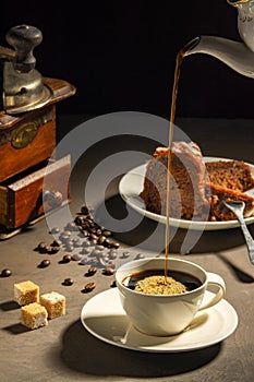 Exposition of chocolate cake with cup a coffee, coffee grinder on background. Black background.