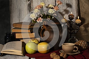 Exposition of hand made clay set on white wooden table, with books, candles, flowers, apple. Tea cup and clay kettle. Vintage styl