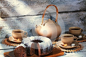 Exposition of hand made clay set on white wooden table and, with tasty chocolate cake. Tea cup and clay kettle.