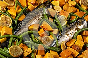 Exposition of healthy and tasty makerel with vegetbles on plate and black table. pumpkin, beans, lemon and makerel.