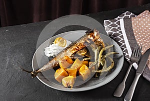 Exposition of healthy and tasty makerel with vegetbles on plate and black table. pumpkin, beans, lemon and makerel.