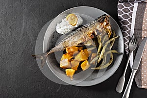 Exposition of healthy and tasty makerel with vegetbles on plate and black table. pumpkin, beans, lemon and makerel.