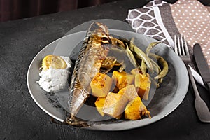 Exposition of healthy and tasty makerel with vegetbles on plate and black table. pumpkin, beans, lemon and makerel.