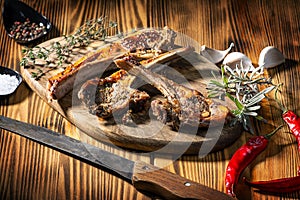 Exposition of mutton, fried lamb, barbecue lamb on wooden plate with chili pepper and garlic on wooden table.