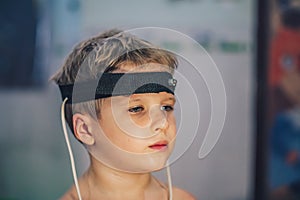Express biofeedback microcurrent rezonans health of organs diagnostic. Sick child boy wear bioresonance head electrodes