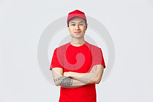 Express delivery, shipping and logistics concept. Confident asian man working in deliver company, wearing red uniform