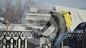 Express food delivery by bike during lockdown and coronavirus epidemic. Man in protective mask with yellow thermo