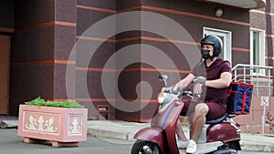 Express food delivery service. Delivery boy wearing red uniform on scooter with isothermal food case box