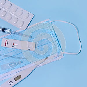 Express positive Langya henipavirus LayV test,Schnelltest, medical mask, syringe,thermometer,medicine on a blue background.The photo
