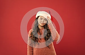 Express positivity. small girl in santa hat. cheerful child red background. winter kid fashion. favorite winter holiday