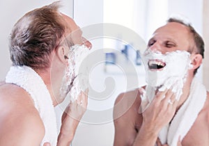 Expressed young man shaving near the mirror photo