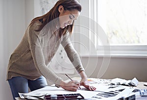 Expressing herself creatively. A young woman working on her portfolio at home.