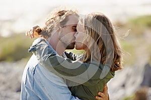 Expressing their love in the outdoors. an affectionate young couple sharing a kiss in nature.