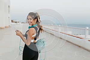 Expressing true positive emotions of joyful young woman in sportswear walking on seafront. Outwork, sportive lifestyle photo