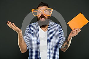 Expressing wonder. Book nerd making a helpless gesture. University male student wearing fancy glasses with lecture notes