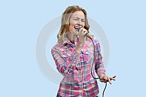 Expressinge young blond woman with microphone is singing a song.