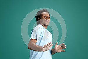 Expression of rejection. Young african guy in casual clothes standing against green studio background