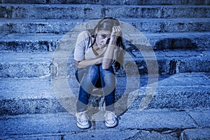 Expressionist edited portrait of young sad and depressed woman or teen girl sitting lonely at street staircase looking desperate a