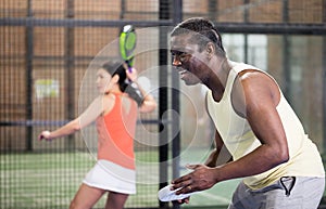 Expressive african american playing paddle ball on closed court