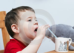 expressive boy drinking orange juice through a plastic straw