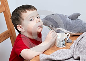 expressive boy drinking orange juice through a plastic straw