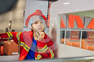 Expressive cute toddler with fireman`s outfit playing fireman