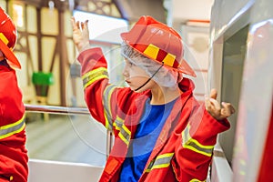 Expressive cute toddler with fireman`s outfit playing fireman