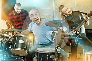 Expressive drummer with his bandmates practicing in rehearsal ro