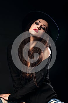 Expressive female model posing in black shirt and elegant hat wi