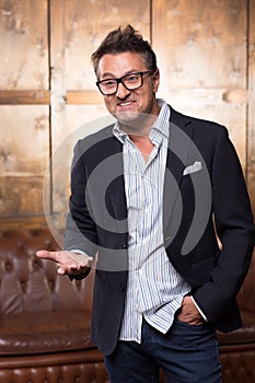 Expressive Frenchman in glasses putting one hand forward and smiling