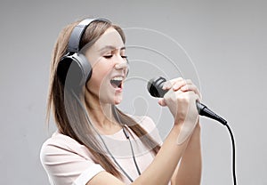 Expressive girl singing with a microphone and headphones