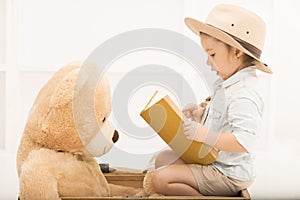 Expressive little girl reading to her teddy bear