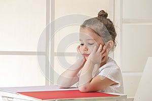 Expressive little girl sitting at the desk waiting