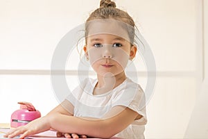 Expressive little girl sitting at the desk waiting