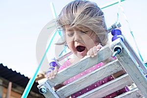 Expressive little girl swing outdoor portrait with come uncurled hairs, child playing