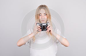 Expressive portrait of a beautiful young surprised blonde woman in a white T-shirt in the studio on a gray background with a