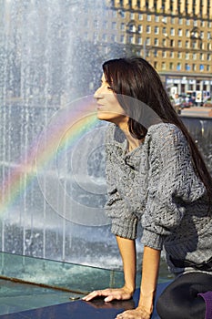 Expressive production figures. girl with bright makeup brunette with long hair in a gray lace sweater Spray Rainbow water fountain