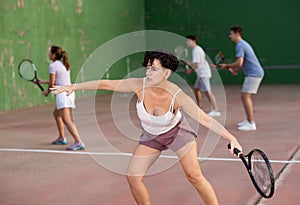 Expressive resolved fit girl playing frontenis ball friendly match on court