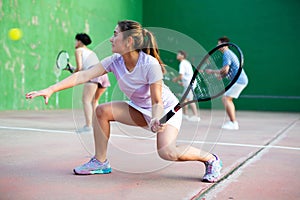 Expressive resolved fit girl playing frontenis ball friendly match on court