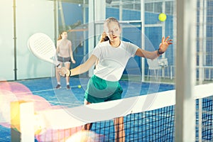 Expressive resolved fit teenage girl playing paddle ball friendly match on small closed court. Concept of competition