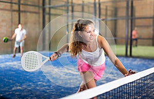 Expressive resolved girl playing paddle ball on closed court