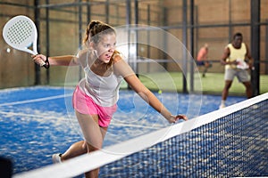 Expressive resolved girl playing paddle ball on closed court