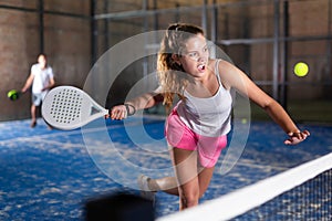 Expressive resolved girl playing paddle ball on closed court